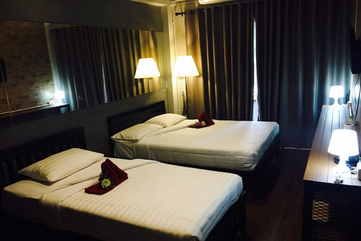A hotel room with two beds, each with white linens and pillows, a large mirror above the beds, and two bedside lamps.