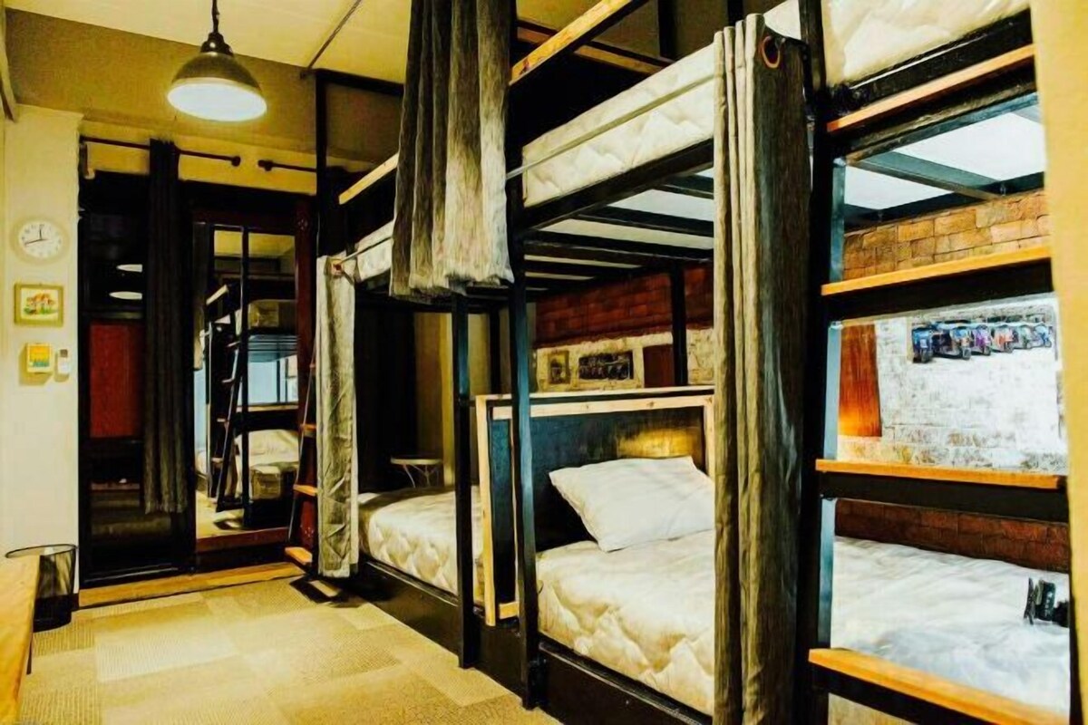 Una habitación con literas, una puerta a la vista y una lámpara colgante.