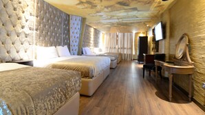 Une chambre d’hôtel avec un grand lit, un lit plus petit, un bureau avec un miroir et un téléviseur fixé au mur.