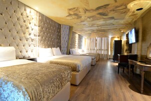 Una habitación de hotel con una cama grande, una cama más pequeña, un escritorio y una silla.