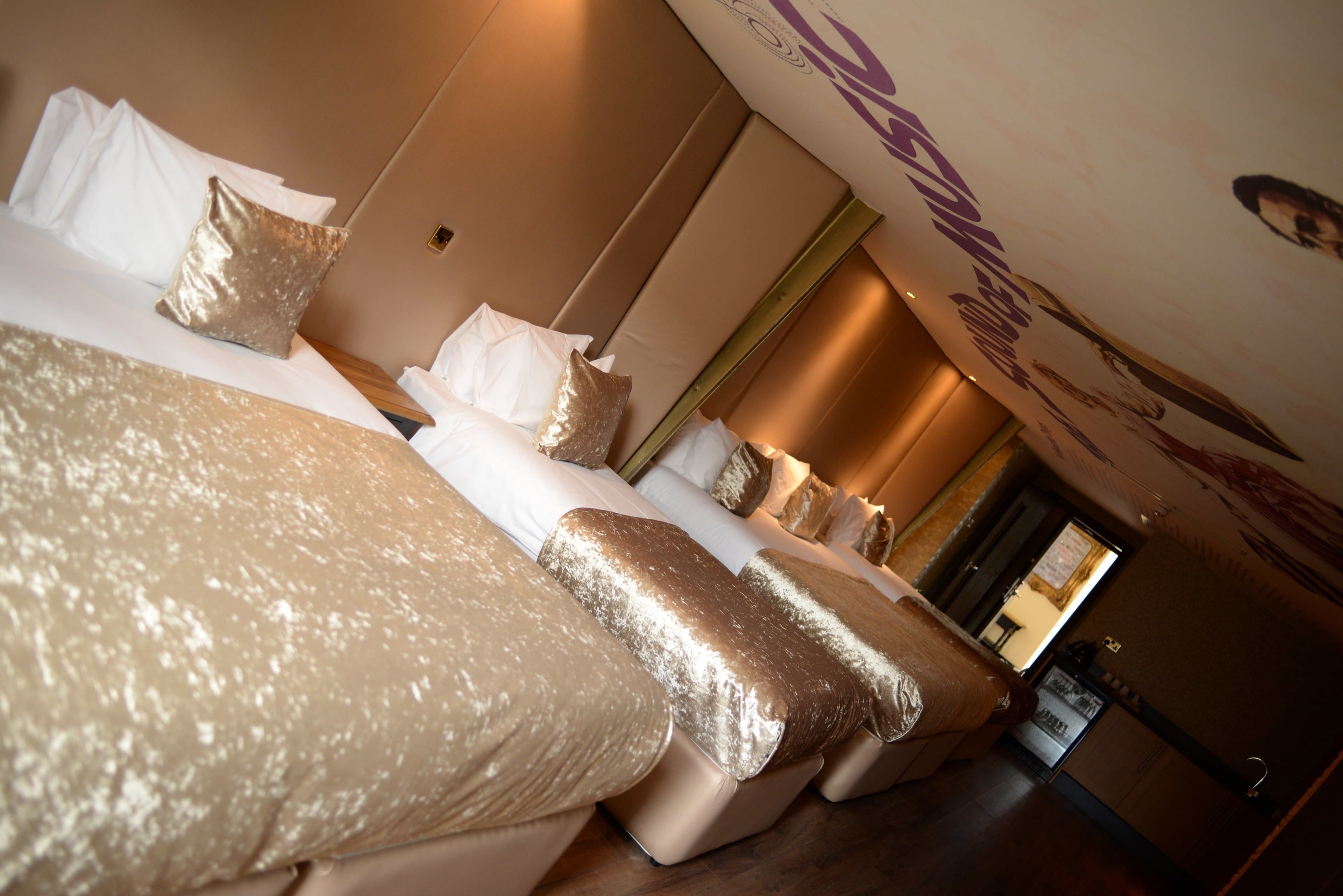 A hotel room with a large bed, multiple pillows, a mirror, and a wall with a poster.