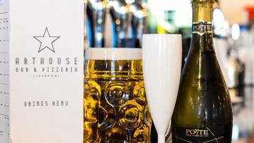 A menu at a bar and pizzeria with a bottle of Prosecco and a glass of beer on a table.