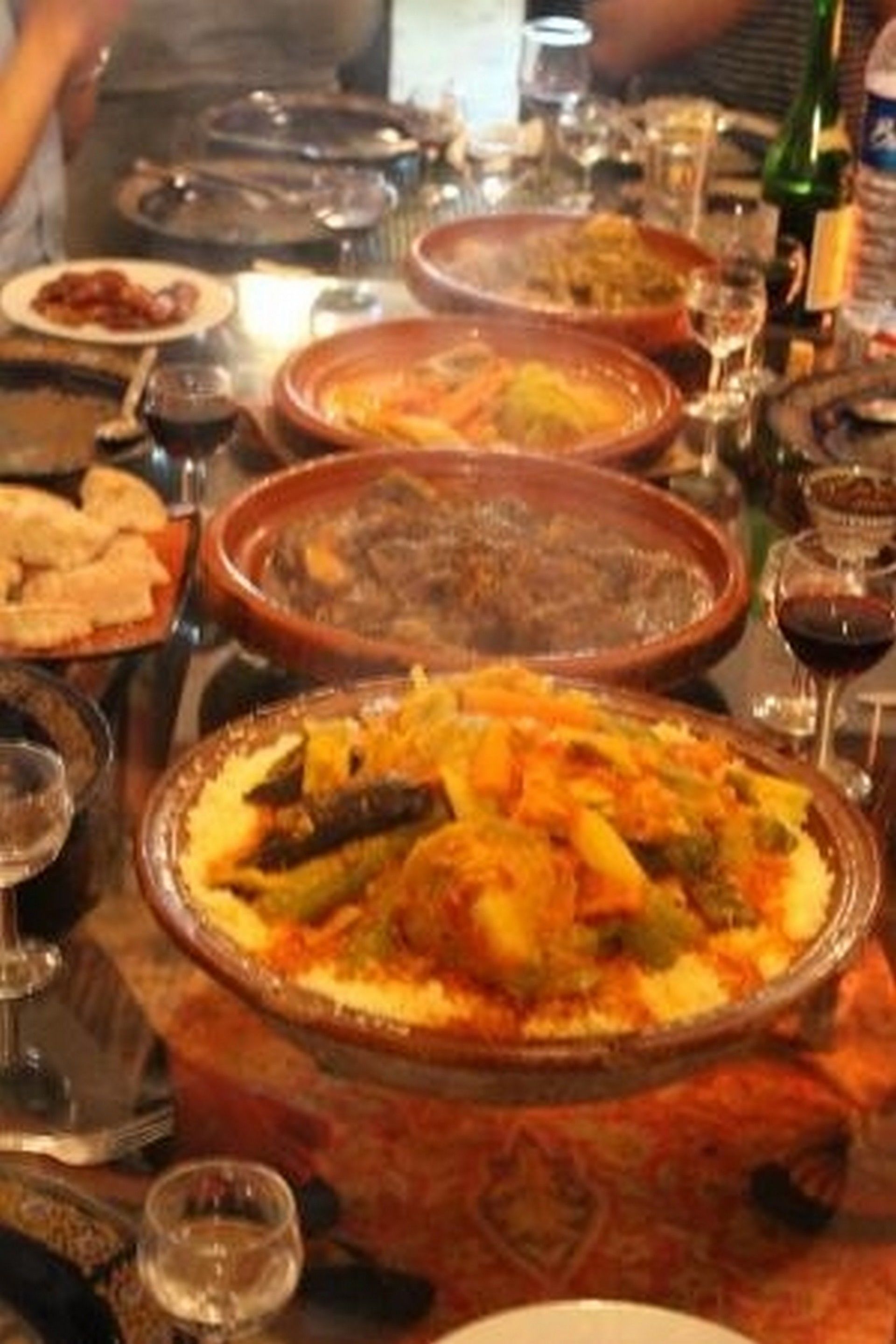 Una mesa con diferentes platos, copas de vino y una botella de agua.