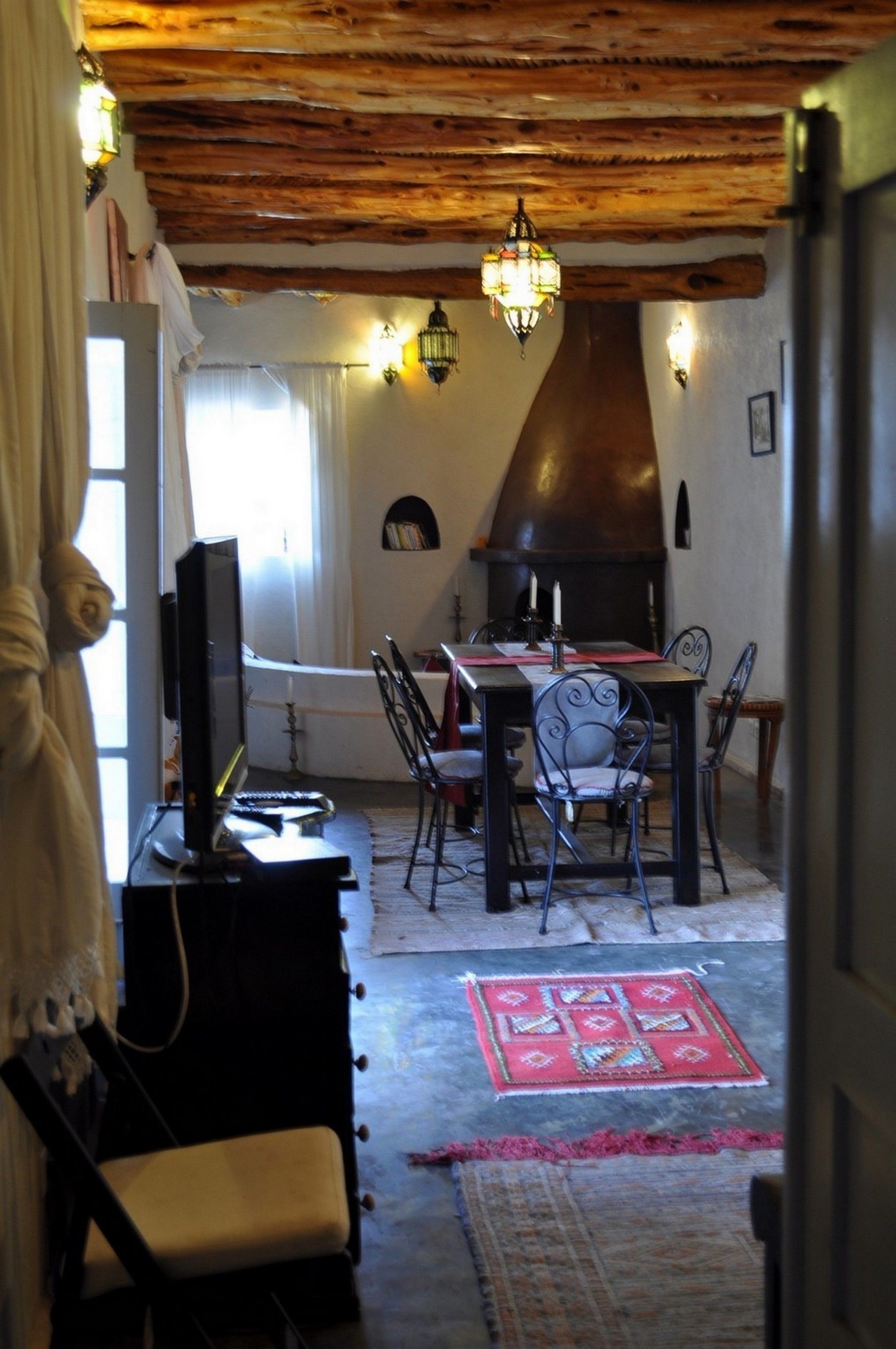 A cozy dining area with a wooden ceiling, a fireplace, and a table set for two.