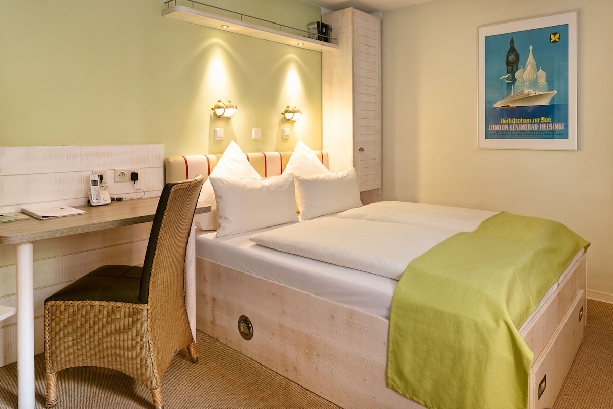 Une chambre d’hôtel avec un lit, un bureau, une chaise et une affiche au mur.