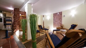 A spa area with wooden lounge chairs, a stone wall, and a wooden table with a bowl. - Hotel Rickmers Insulaner (Helgoland)