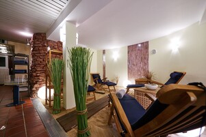 Un área de spa con sillones de madera, una pared de piedra y una mesa de madera con un cuenco.