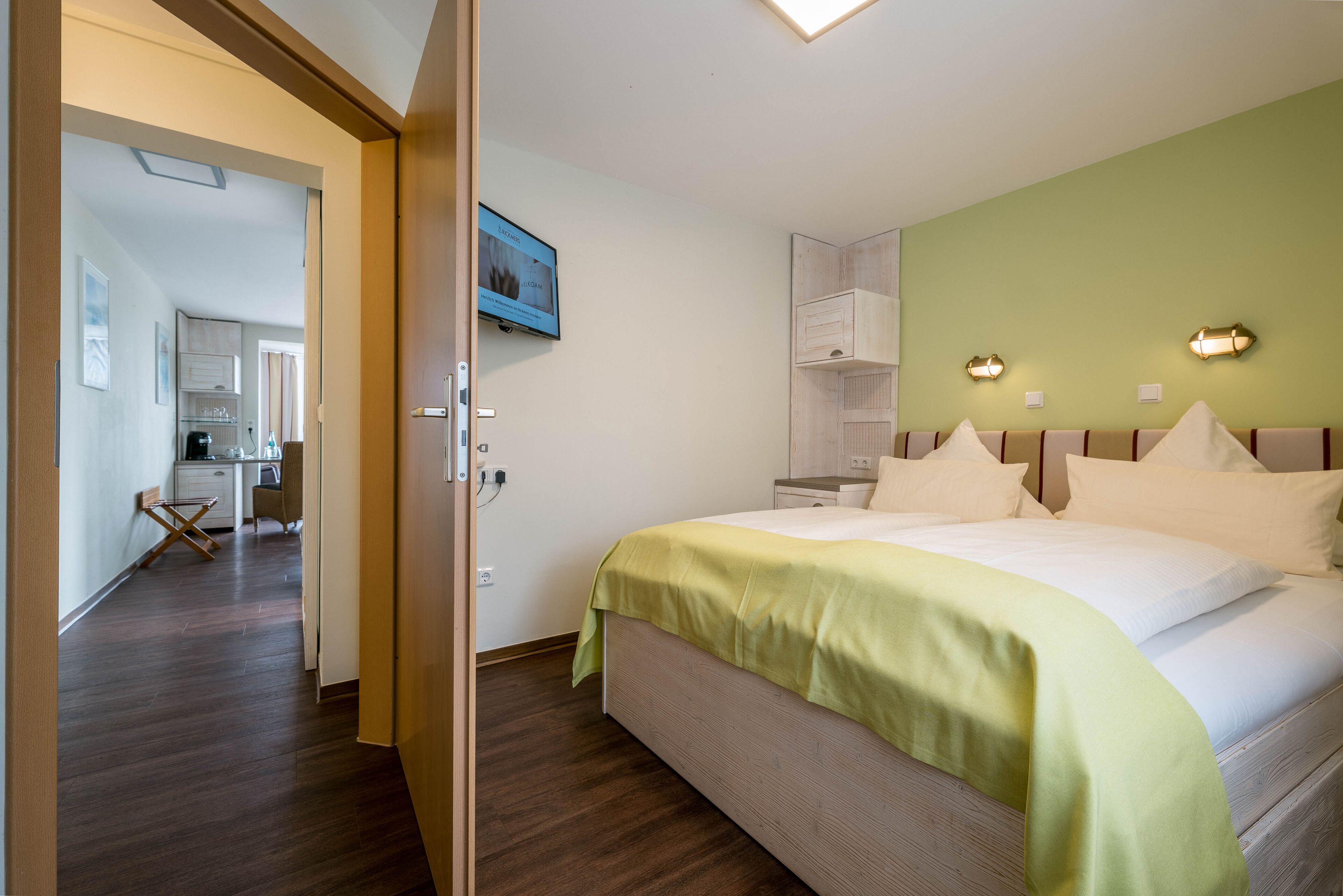 A hotel room with a bed, a desk, and a kitchenette.