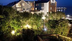 A modern multi-story building with large windows and a balcony, surrounded by lush greenery. - Hotel Rickmers Insulaner (Helgoland)