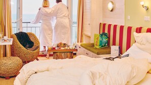 A hotel room with a balcony, a wicker chair, a bed, a small table with breakfast items, and a view of the sea. - Hotel Rickmers Insulaner (Helgoland)