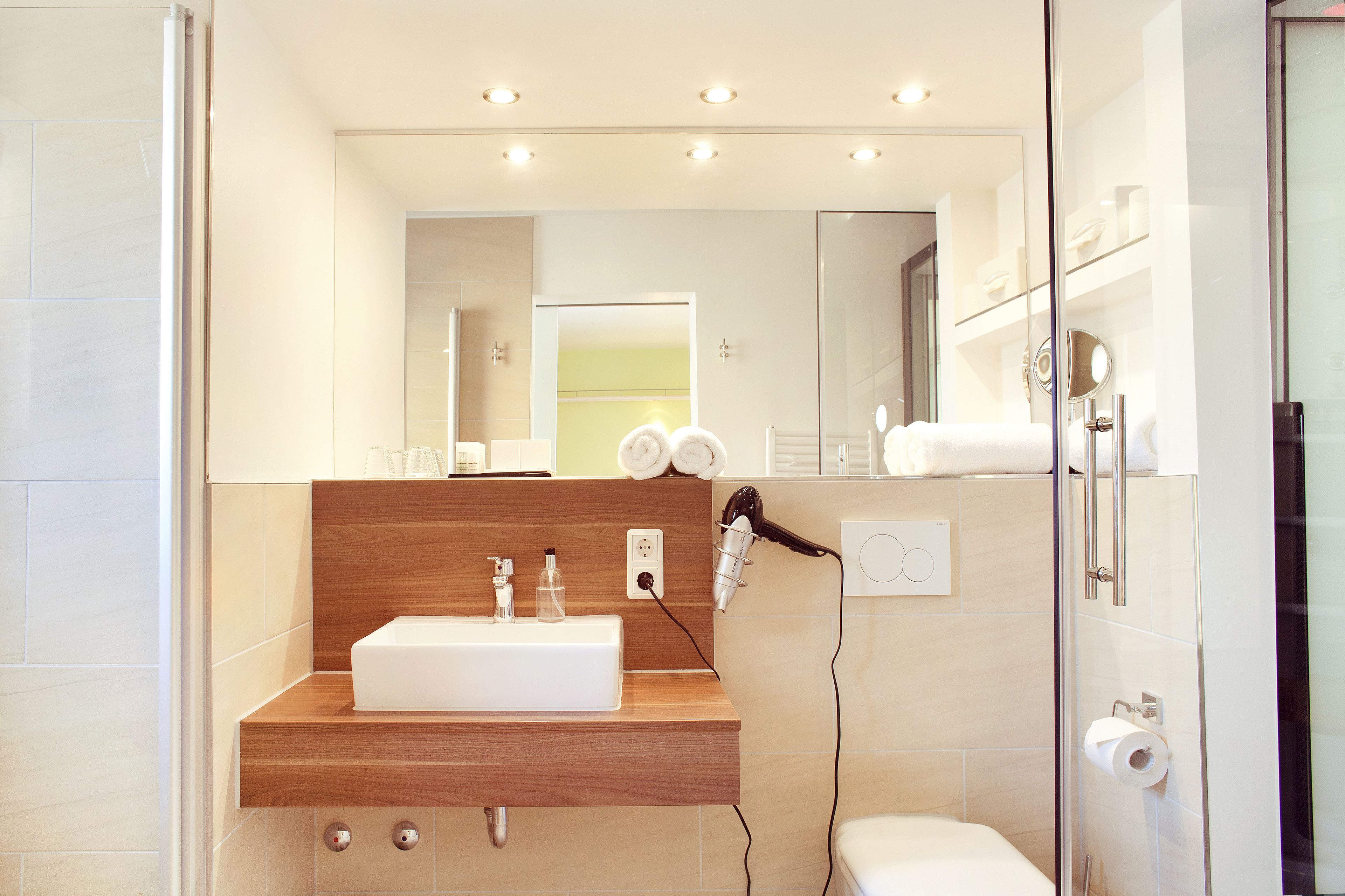 Un baño moderno con tocador de madera, un espejo grande y cabina de ducha de vidrio.