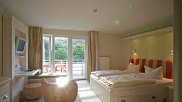 A bedroom with a bed, a desk, a chair, and a view of the outdoors.