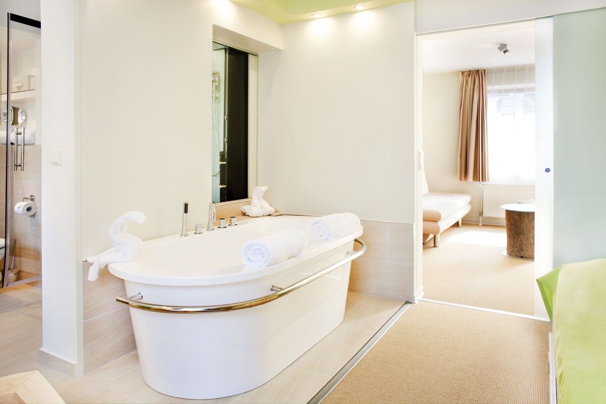 A modern bathroom with a freestanding bathtub, a mirror, and a shower area.