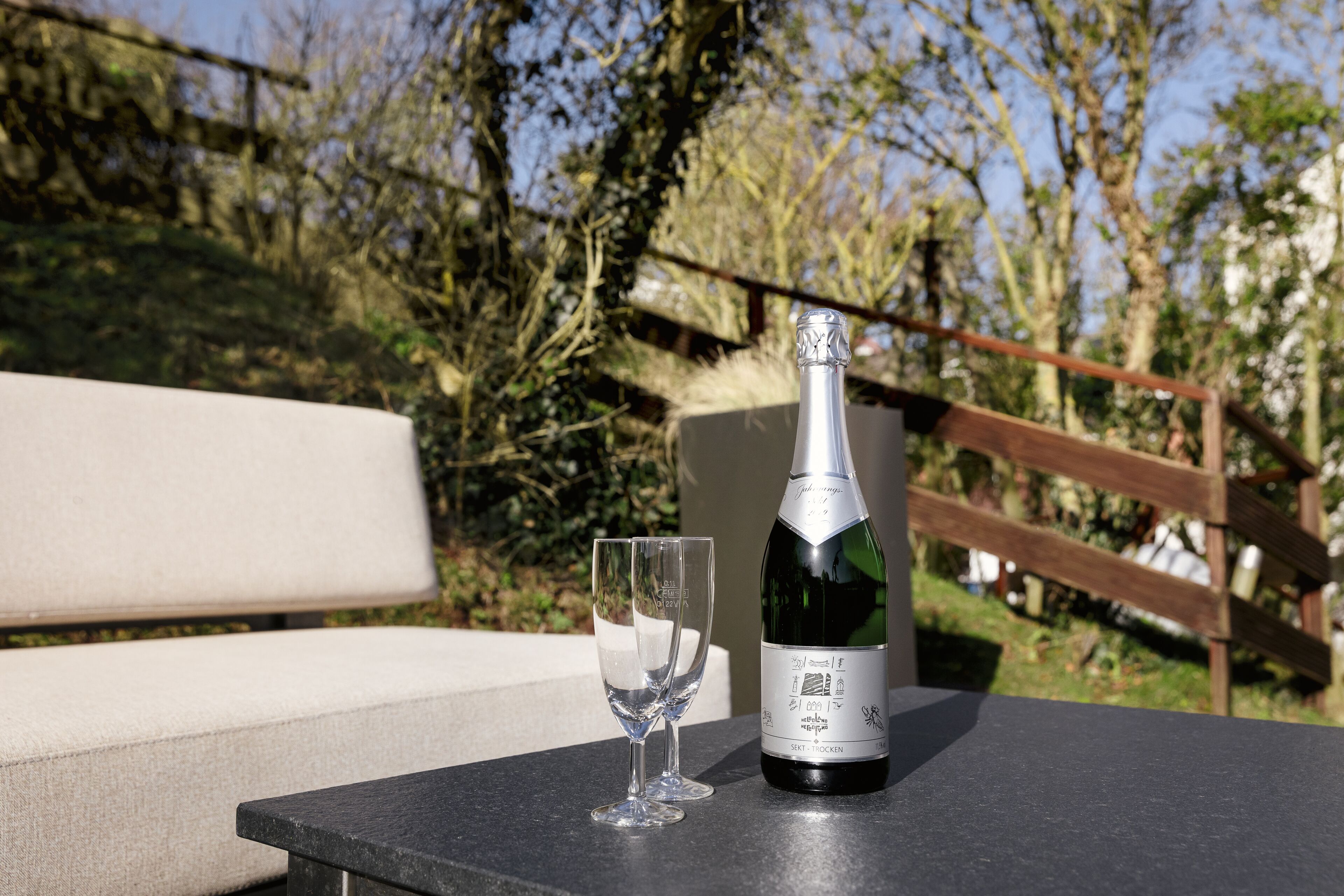 A bottle of wine and an empty glass on a table outdoors.