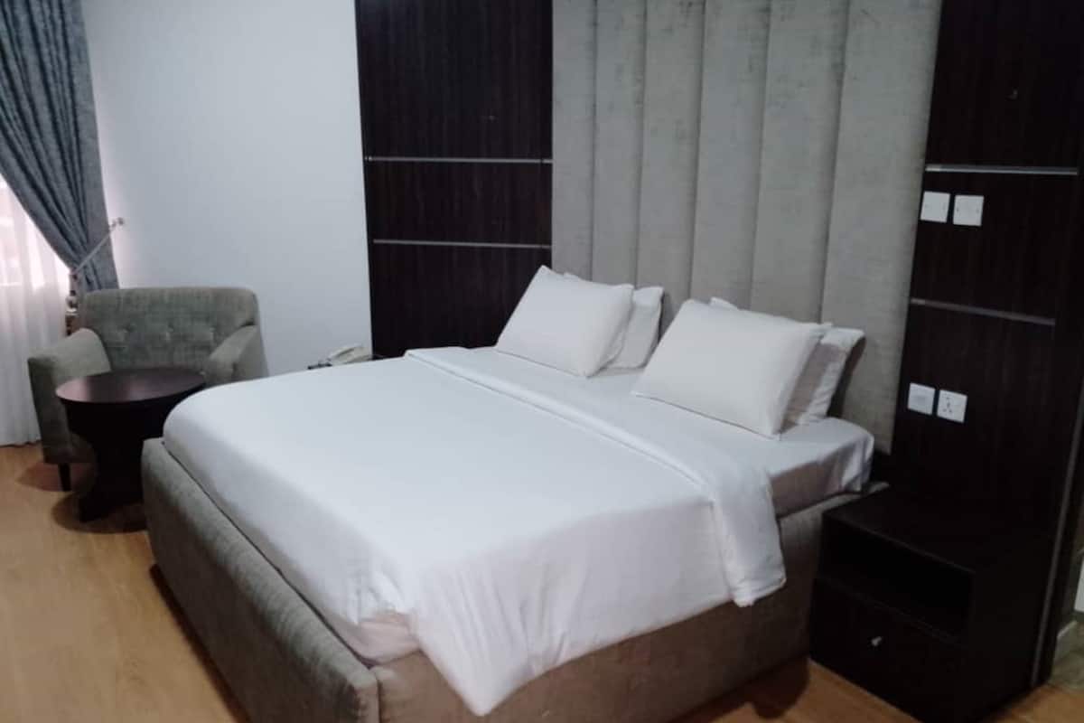 A modern bedroom with a large bed, a small round table, and a chair.
