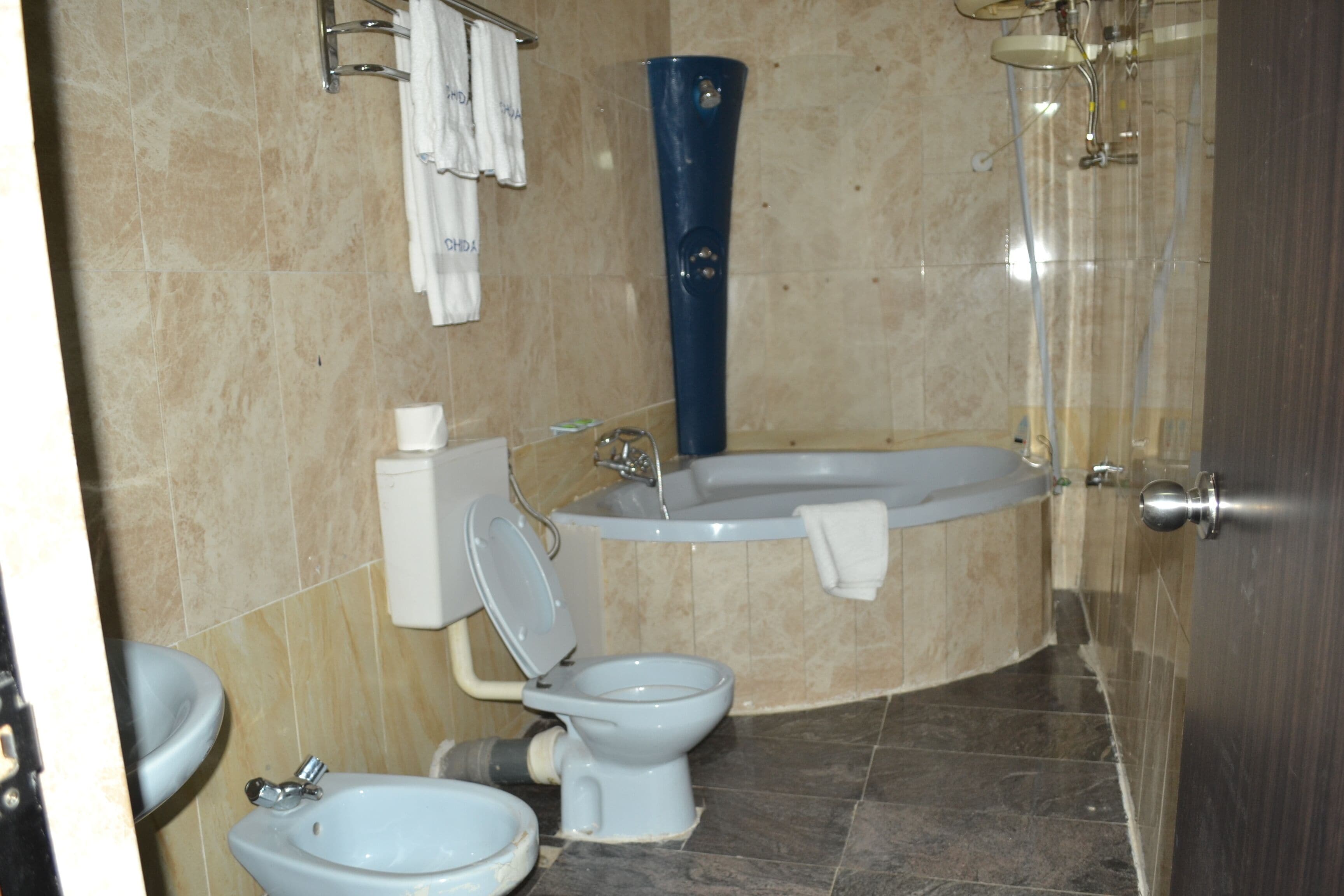 A bathroom with a toilet, bidet, bathtub, and a towel rack.
