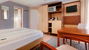 A hotel room with a bed, a wooden desk, a television, and a wardrobe. - Hotel Helgoländer Klassik (Helgoland)