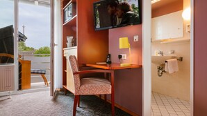 A hotel room with a desk, chair, television, and a bathroom with a sink and towel rack. - Hotel Helgoländer Klassik (Helgoland)