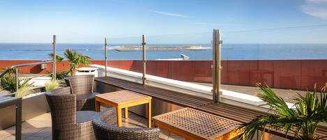 Una terrazza con mobili in vimini e vista sul mare.