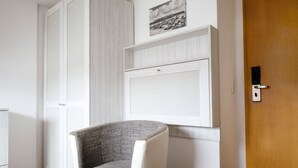A room with a white wardrobe, a mounted picture, and a wooden door. - Hotel Felsen-Eck (Helgoland)