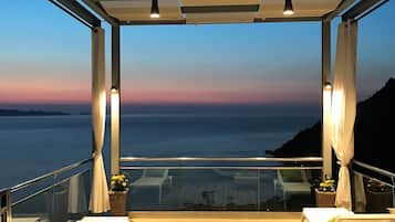 A terrace with a view of the sea, featuring a table, chairs, and a small plant.