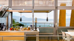 Una cocina moderna con un amplio ventanal que ofrece una vista panorámica, suelo de madera y una zona de comedor con mesa y sillas.