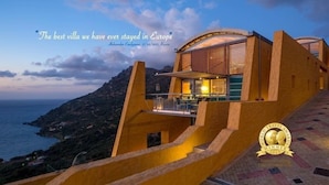 Una villa de diseño moderno, con una escalera destacada que lleva a una terraza con vistas al mar.