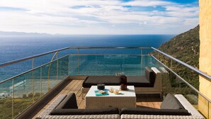 Un balcón con barandilla de vidrio que ofrece vistas al mar.