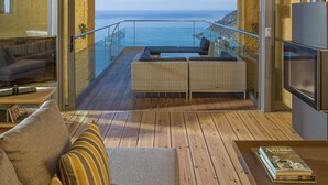 Un salón moderno con un gran ventanal que da a un balcón con vistas al océano.