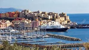 Paisatge urbà costaner amb un port, embarcacions i edificis.