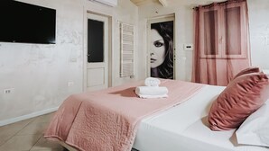 Un dormitori amb llit, televisió, porta i cortina de bany.