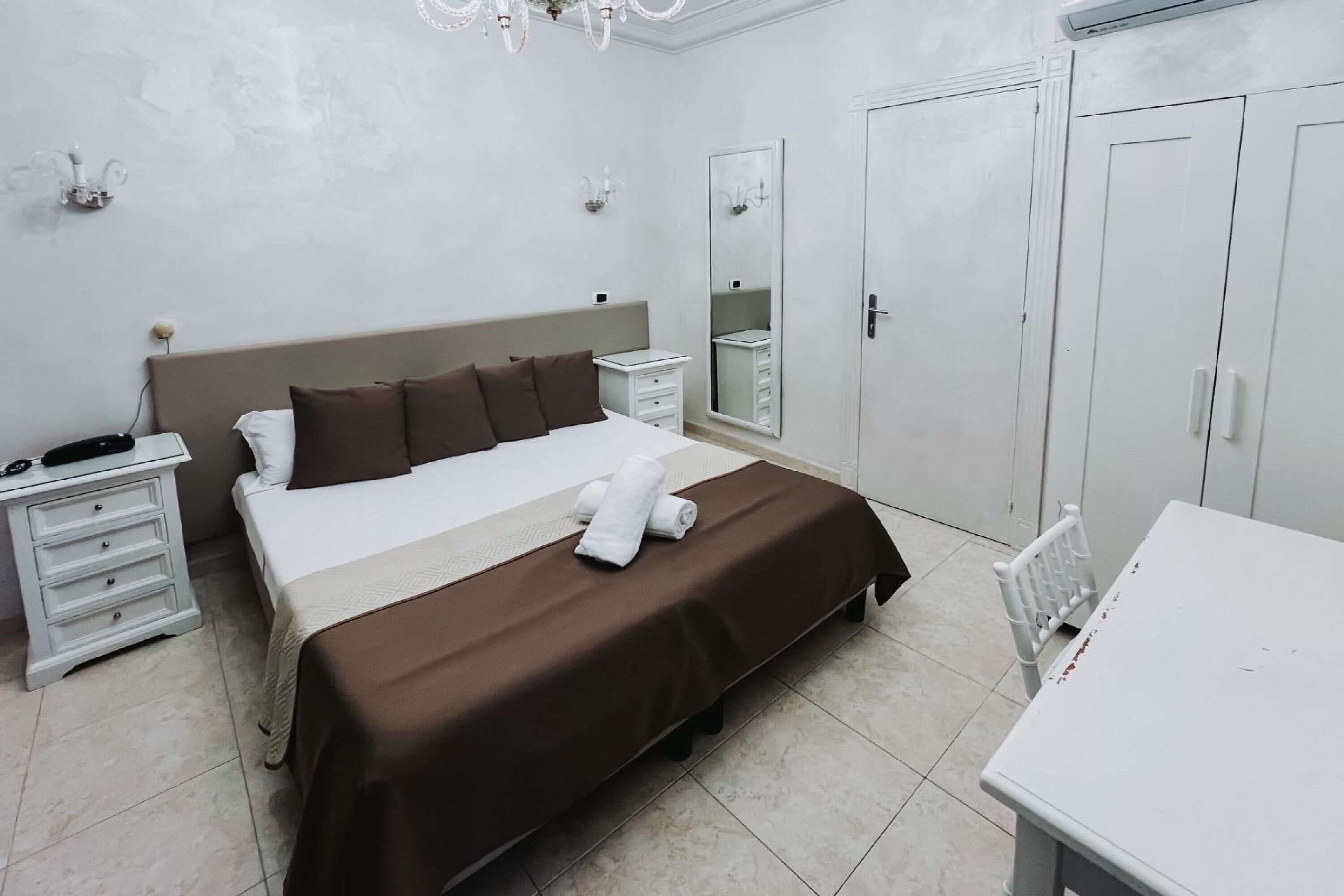 Une chambre d’hôtel avec un grand lit, une table de chevet, un miroir, une armoire et une petite table.