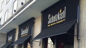 A building with multiple storefronts, including one named 'Schatzkristl' with a sign indicating it is a music bar. - 1 bedroom apartment in prime location (Mannheim)