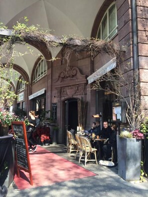 An outdoor cafe with tables and chairs, a red carpet, and a sign that reads "DORCHE".