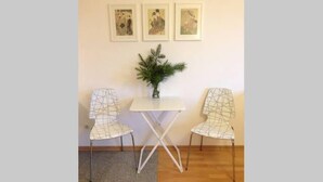 A room with a white table and two white chairs with a geometric pattern. There are three framed artworks on the wall above the table. - 1 bedroom apartment in prime location (Mannheim)