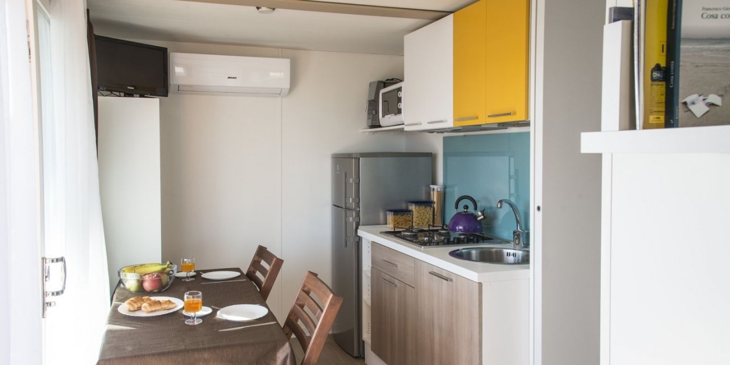 Une cuisine compacte comprenant un coin repas, un réfrigérateur, une cuisinière et un évier.