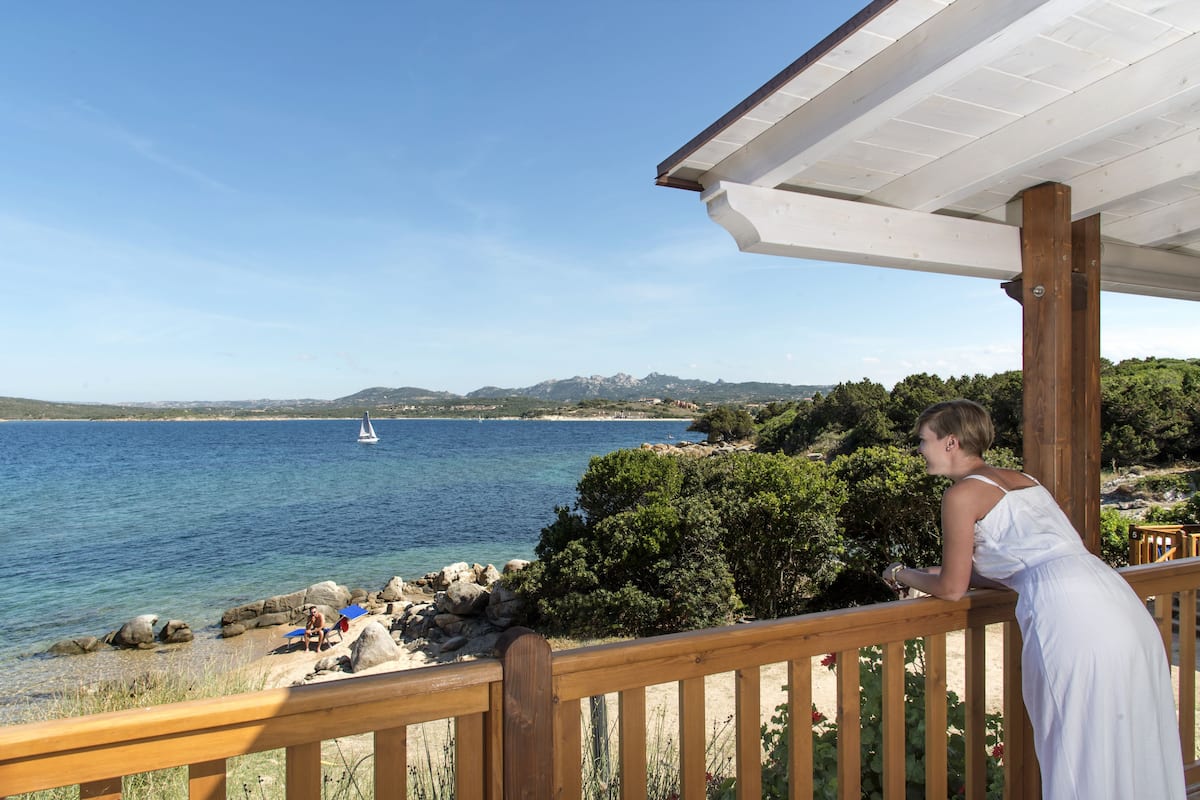 A wooden deck overlooking a coastal area with a clear view of the sea and a sailboat.