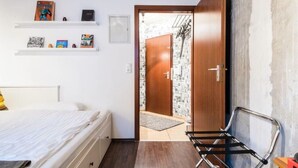 A bedroom with a bed, a chair, a wooden door, and a shelf with books and a picture frame. - Charming Hipster Flat (Mannheim)