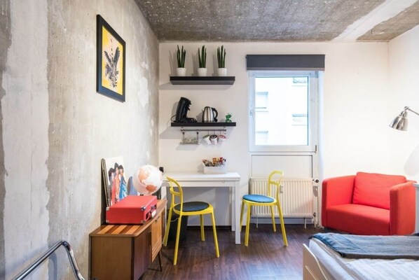 A compact room with a white desk, two yellow chairs, a red sofa, and a radiator. - Charming Hipster Flat (Mannheim)