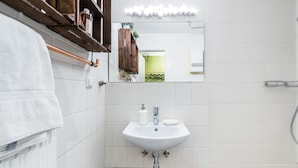 Une salle de bain avec un lavabo blanc, un plan de toilette en bois et un miroir au-dessus du lavabo.