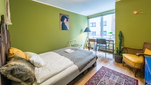Une petite pièce comprenant un lit, un bureau, une chaise et une plante en pot.