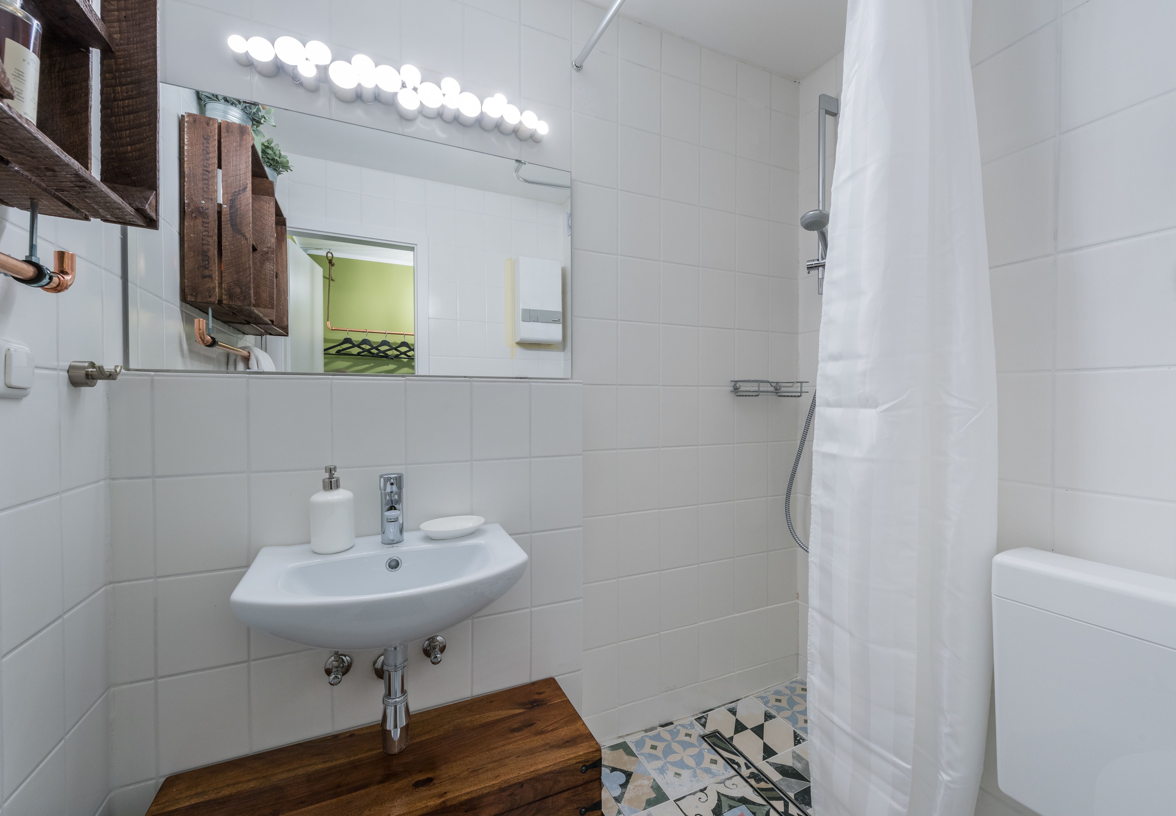 Une salle de bain avec un lavabo blanc, un meuble-lavabo en bois et un rideau de douche.