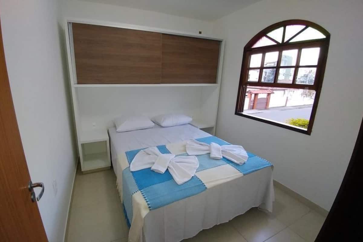 A bedroom with a bed, a window, and a door.