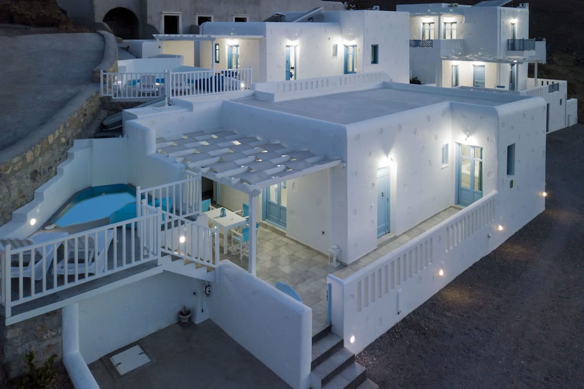 Ein weißes Gebäude mit mehreren Balkonen, einem Pool und einer kleinen Außenbereich-Sitzgelegenheit.