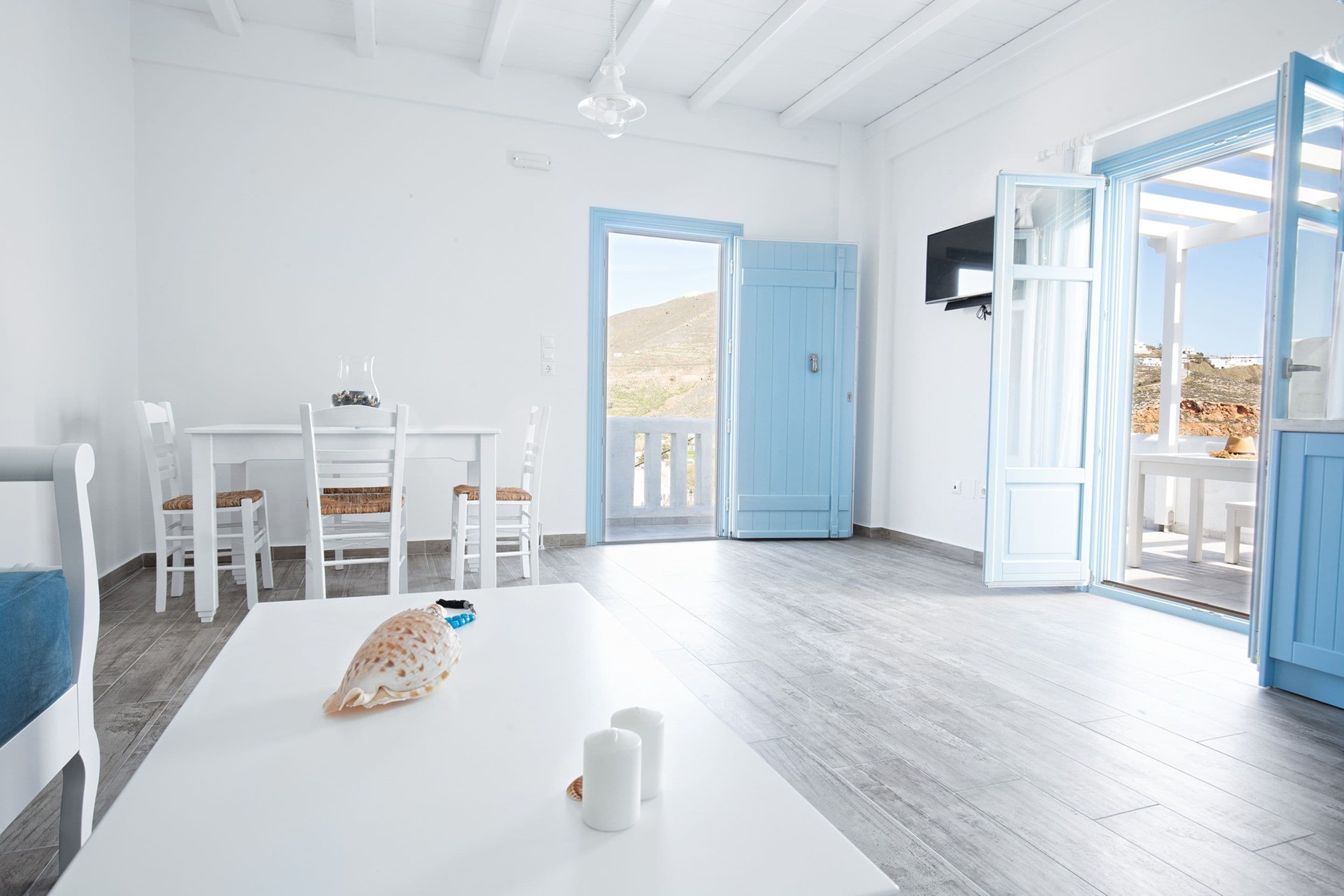 A bright, open room with a white table, chairs, and a view of the outdoors.