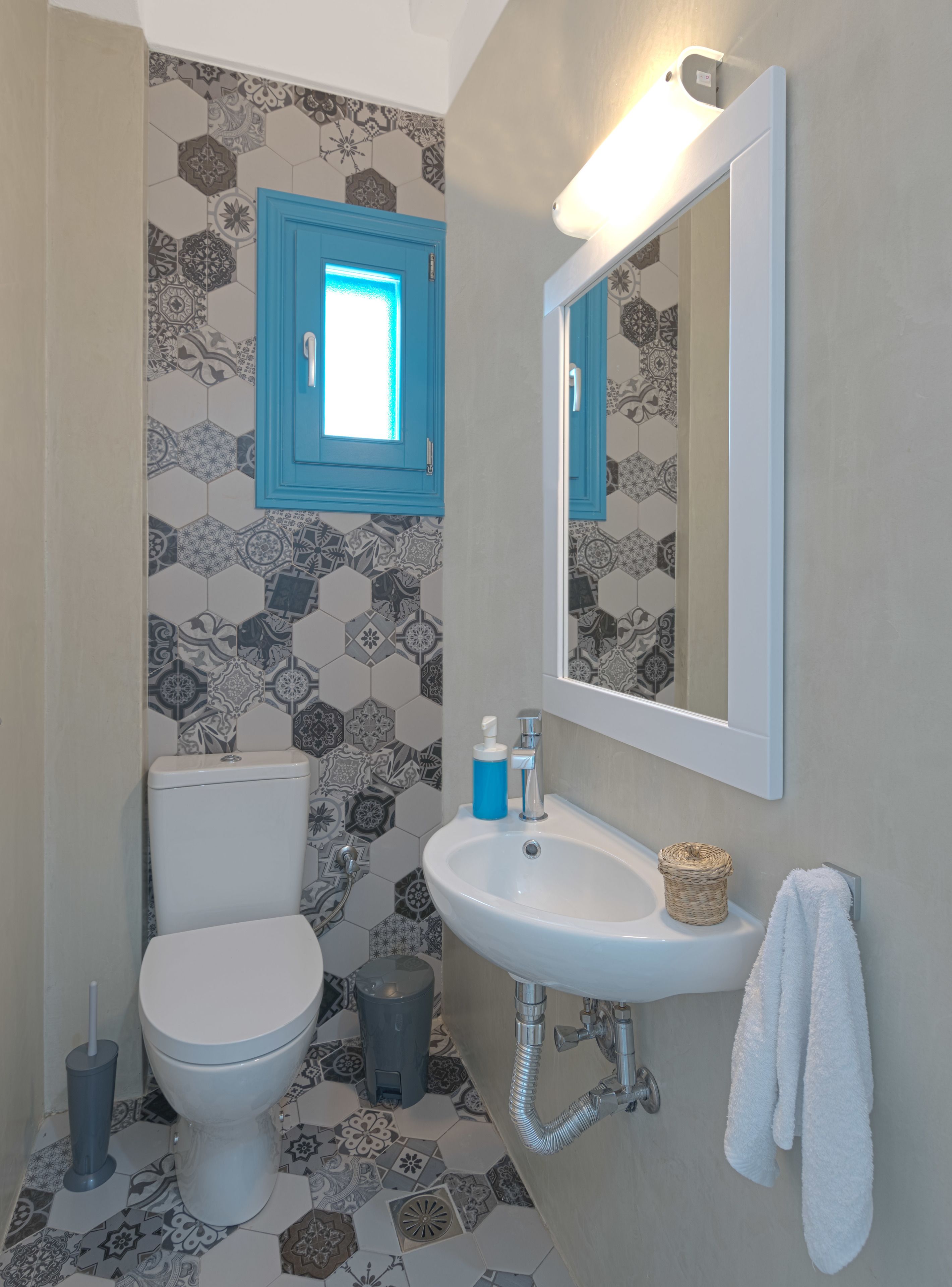 A bathroom with a toilet, sink, and mirror.