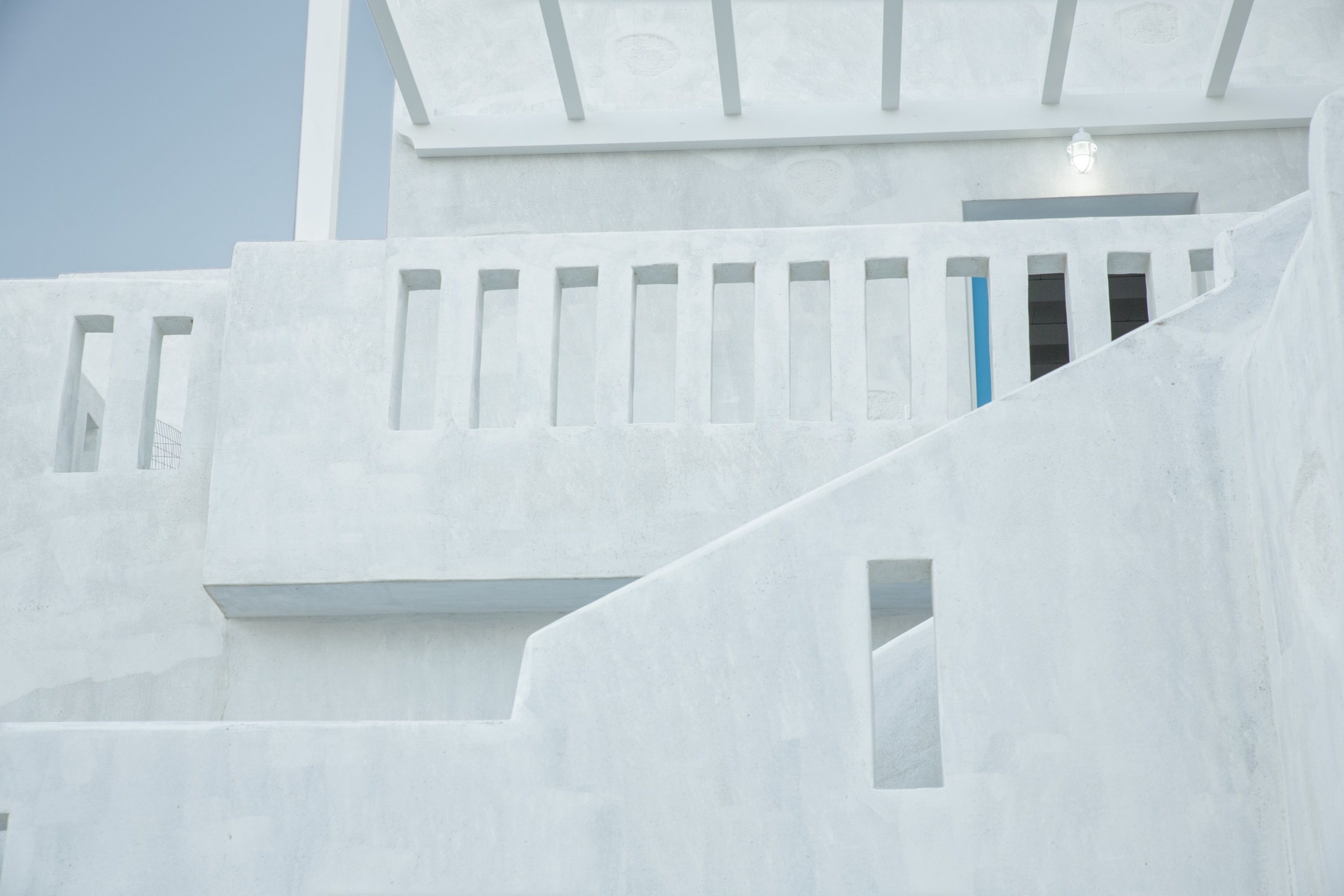 A white building with a staircase and a blue door.