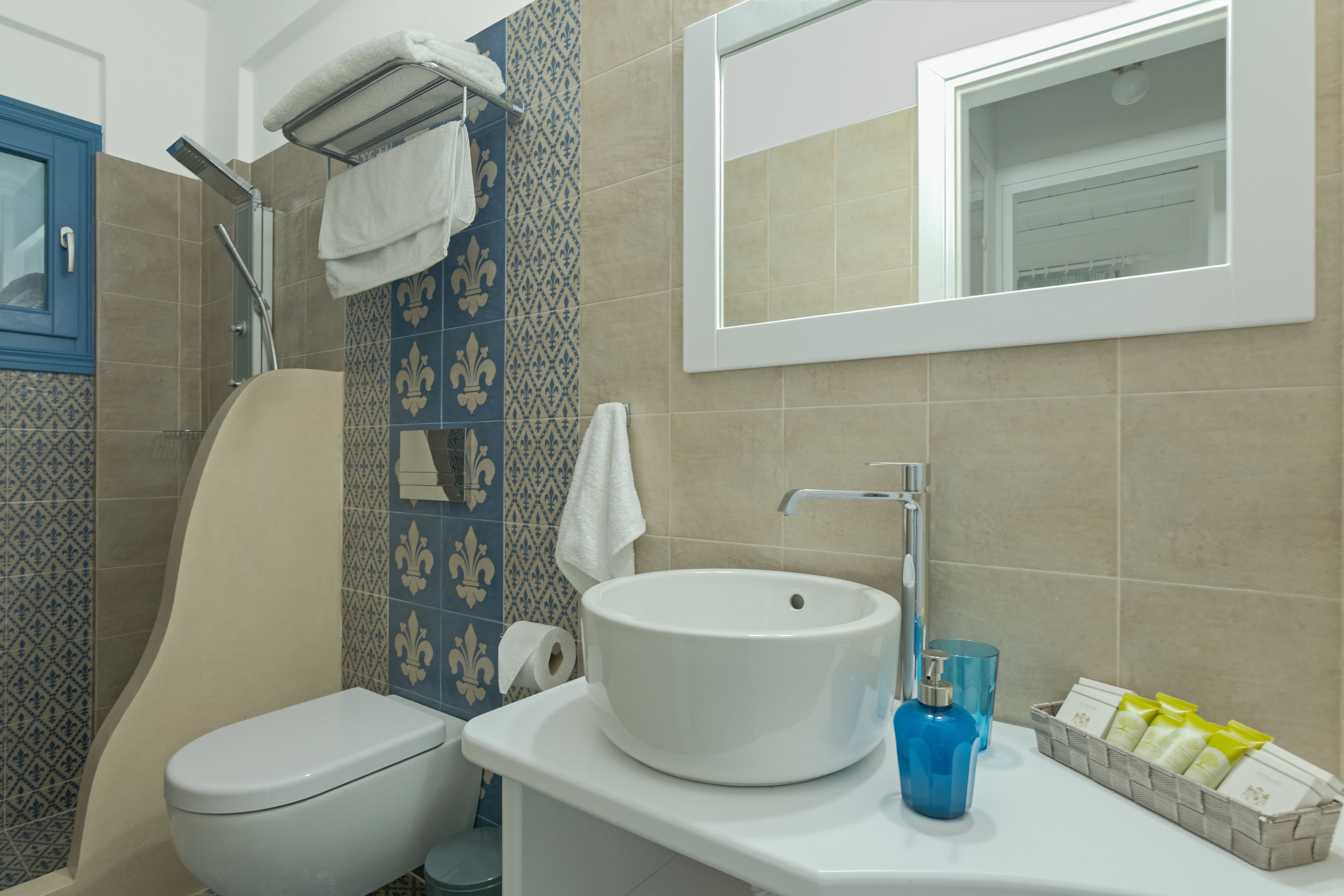 A bathroom with a white sink, a toilet, and a shower. There are towels hanging on a rack and a mirror above the sink.