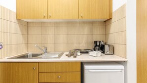A kitchen with wooden cabinets, a sink, a dishwasher, and a countertop with a toaster and other appliances. - Alterego Studios (Zakynthos)