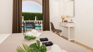 A hotel room with a bed, a desk, a chair, a mirror, and a view of a pool. - Alterego Studios (Zakynthos)